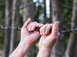 hands clasped on barbed wire