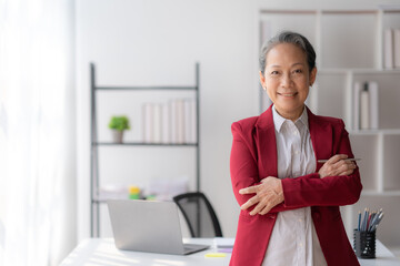 Asian senior businesswoman crossed arms smiling happily at office.