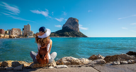 Woman sitting and looking at Calpe rock and mediterranean sea view