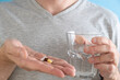 Man taking antiphlogistic white pill with a drug for protect stomach medicine capsule on blue background