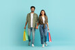 © Prostock-studio - Happy multiracial young couple holding shopping bags, walking on blue