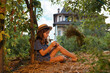 © _KUBE_ - Alone pretty caucasian little girl wearing straw hat sits on the ground in garden. The concept of local farming and psychology