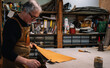 © victor cuenca lopez - side view of a leather craftsman who dabs the edges of a piece of leather with a waterproof varnish