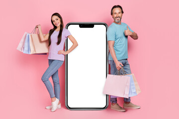 Poster - Full length photo of two people hold packages show thumb up recommend huge phone isolated on pink color background