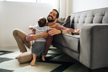 Wall Mural - Happy father hugging little son at home. Happy Brazilian father embracing son