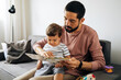 © kleberpicui - Happy father and toddler son reading book at home