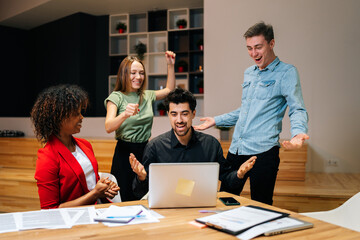 Wall Mural - Portrait of happy excited startup team looking at laptop screen, rejoicing and expressing happiness, cheerful colleagues congratulating success. Creative diverse people wondering looking at screen.