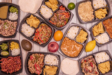 Set Of Food Delivery Containers Filled With Mexican Recipes With Stews, Nachos, Rice, Pies, Wheat Pancakes, Whole And Sliced Citrus