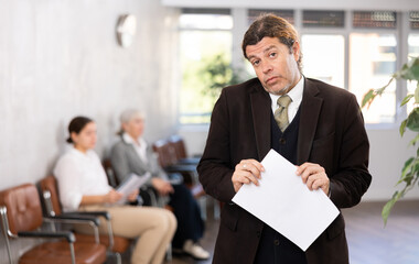 Wall Mural - Adult man in business suit posing with documents in his hands in office space