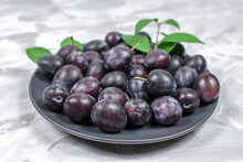 Fresh Plums On A Plate Gray Concrete Background. Close-up. Selective Focus.