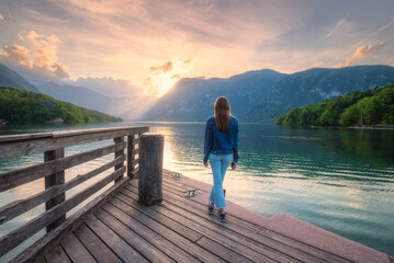 Wall Mural - woman and mountains reflected in lake at sunset in autumn