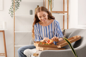 Wall Mural - Young woman taking slice of tasty pizza from box at home