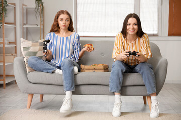 Canvas Print - Young women with tasty pizza playing video game at home