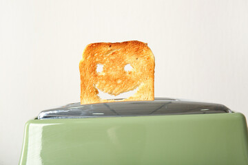 Funny slice of bread in modern toaster on white background