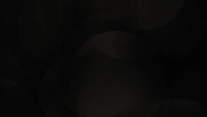 Wall Mural - Vertical Movement of Large Light Bokeh on Black. Soft shimmering motion of light defocused circles. Abstract flow moving bokeh lights 4K background.