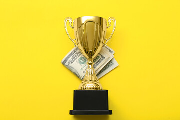 Gold cup with money on yellow background