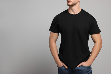 Man wearing black t-shirt on light grey background, closeup. Mockup for design