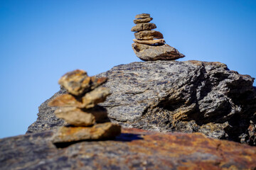 Flat gray stones piled up forming a pyramid and marking the path of a path in the mountains