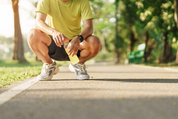 Wall Mural - man jogging and walking on the road at morning with Energy Drink water, adult male in sport shoes running in the park outside. Exercise, wellness, healthy lifestyle and wellbeing concepts