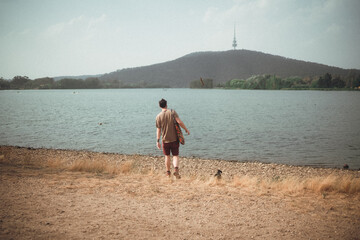 Wall Mural - Man walking at Lake Burley Griffin with small dog