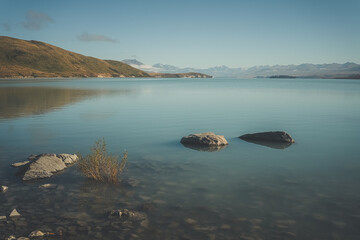 Wall Mural - Stones in large green lake, New Zealand. Lake Wanaka