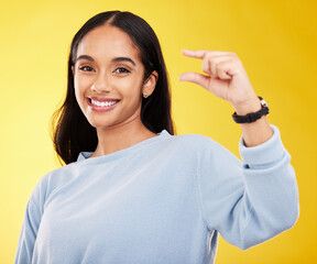 Wall Mural - Showing, small and portrait of a woman with hands isolated on a yellow background in a studio. Happy, measurement and a girl with a review, gesturing size and opinion with fingers on a backdrop