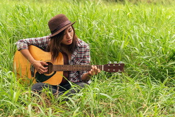 Young women playing acoustic guitar outdoor in green park. Woman person playing acoustic guitar music instrument at home, young Asian musician girl lifestyle in beautiful nature. Happy guitarist