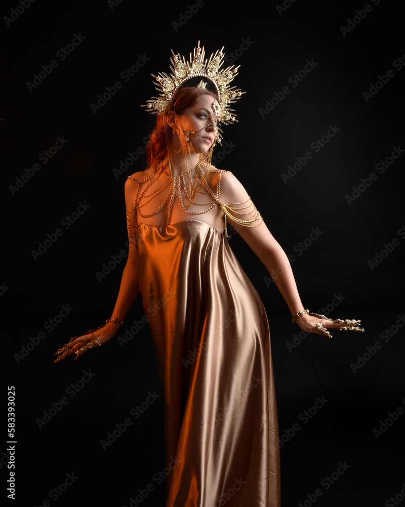 Close up fantasy portrait of beautiful woman model with red hair, goddess  silk robes & ornate gold crown. Posing with gestural hands reaching out,  isolated on dark studio background Stock Photo |