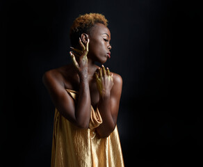  fantasy portrait of beautiful african woman model with afro, goddess silk robes and ornate floral wreath crown. gestural Posing holding golden flowers. isolated on dark  studio background 