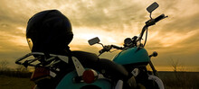 Back, Rear View. Retro Blue Chopper Motorcycle. Helmet, Hard Hat Stands On Seat. Sunset Horizon Line Background. Black Sea Coast. Sunset Cloudy Sky.