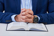 Closeup, hands and man with bible, praying and guidance with higher power, hope and spiritual. Zoom, male and Christian with holy book, scripture and religious with faith, Catholic text and belief