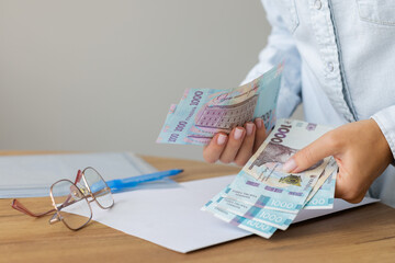 Wall Mural - Woman holding Ukrainian 1000 bill banknotes. Count Ukrainian money