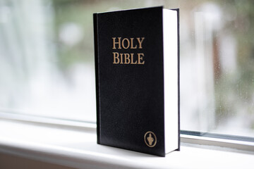 Religious book holy bible hardback black standing window sill help guidance god belief 