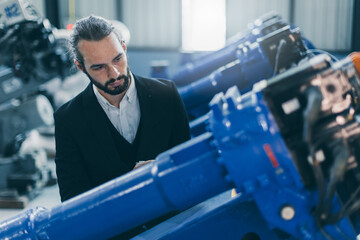 Wall Mural - Businessman manager in suit working in machinery factory robot assembly plant looking check products inventory for industry products business