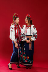 Wall Mural - Ukrainian women in traditional ethnic clothing and floral red wreath on viva magenta studio background. National embroidered dress call vyshyvanka. Pray for Ukraine