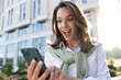 © opolja - Young business woman wearing professional look smiling confident at the city using smartphone.