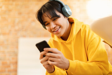 Sticker - Teenager Guy Using Phone Wearing Earphones Listening Music Online Indoors