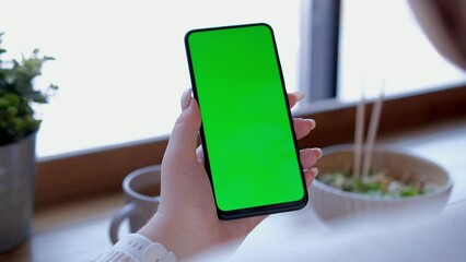 Use green screen for copy space closeup. Chroma key mock-up on smartphone in hand. Woman holds mobile phone 4K