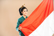 © Odua Images - asian woman in green kebaya standing grabbing the indonesian flag on isolated background