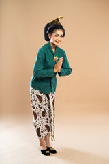 Wall Mural - javanese woman in green kebaya standing bent over with hands put together on isolated background