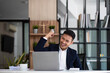 Happy young businessman looking at laptop computer in office, Excited asian man working at his workplace at modern co-working, successful people