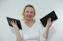 Adult Happy Satisfied Woman Holding Two Tablets Of Large Gadgets On Open Palms In Hands. She Is Smiling Space For Text Online Training Equipment Repair Good Buy Gift White Clothes Manicure