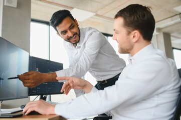 Two diverse crypto traders brokers stock exchange market investors discussing trading charts research reports growth using pc computer looking at screen analyzing invest strategy, financial risks.