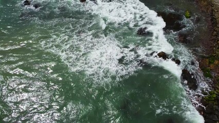 Wall Mural - Aerial view from above of the sea waves at the rocky shore. Ocean coast. Calm beautiful video on the background for tourism, design and advertising