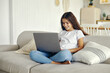 © Alex Tihonov - Cute 12s girl use laptop sit on sofa in living room