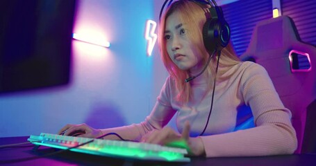 Wall Mural - Happy Gamer endeavor plays online video games tournament with computer neon lights, young woman wearing gaming headphones intend to do playing live stream games online at home