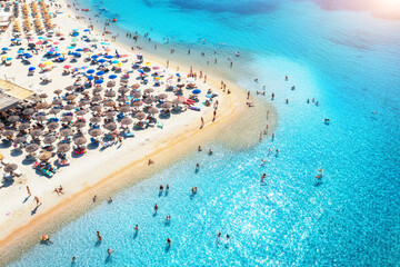 Canvas Print - Aerial view of colorful umbrellas on beach, people in blue sea