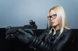 An intelligent girl in glasses takes aim from a pistol with a red dot sight.