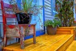 © Dolores  Harvey - The steps to a white colored house with blue trim. There's an old school chair painted red and peeling on the stoop. There's a black flower pot with greenery and a brown pot with mums on the stoop.