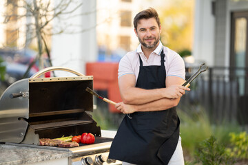 Barbecue master. Middle aged hispanic man in apron for barbecue. Roasting and grilling food. Man hold cooking utensils barbecue. Roasting meat outdoors. Barbecue and grill. Cooking meat in backyard.